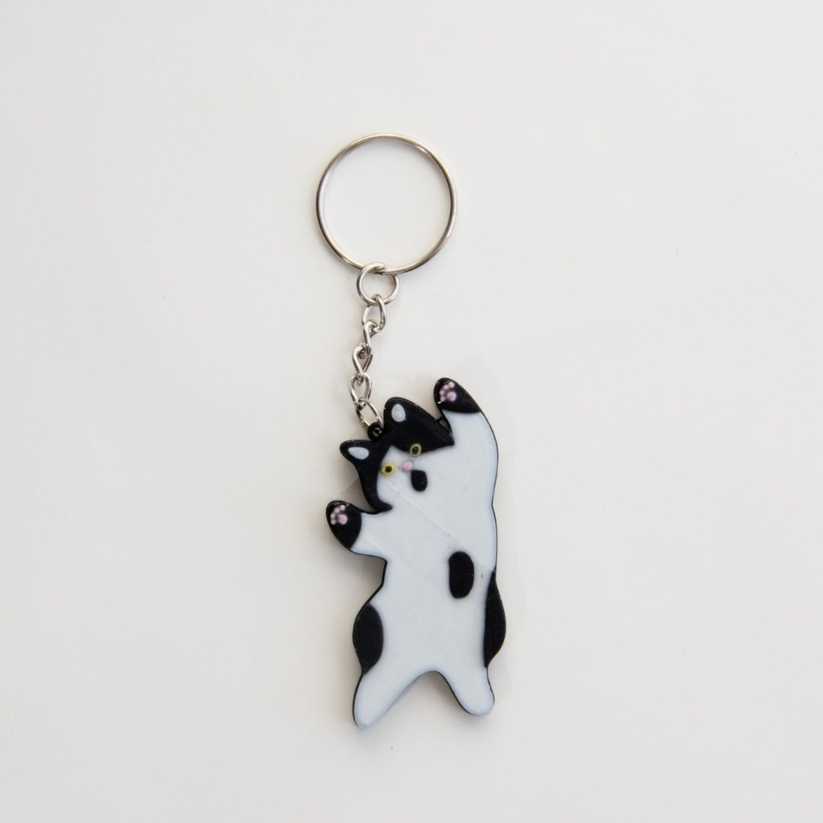 Black and white stretching cat keyring with silver-tone ring and pink paw details