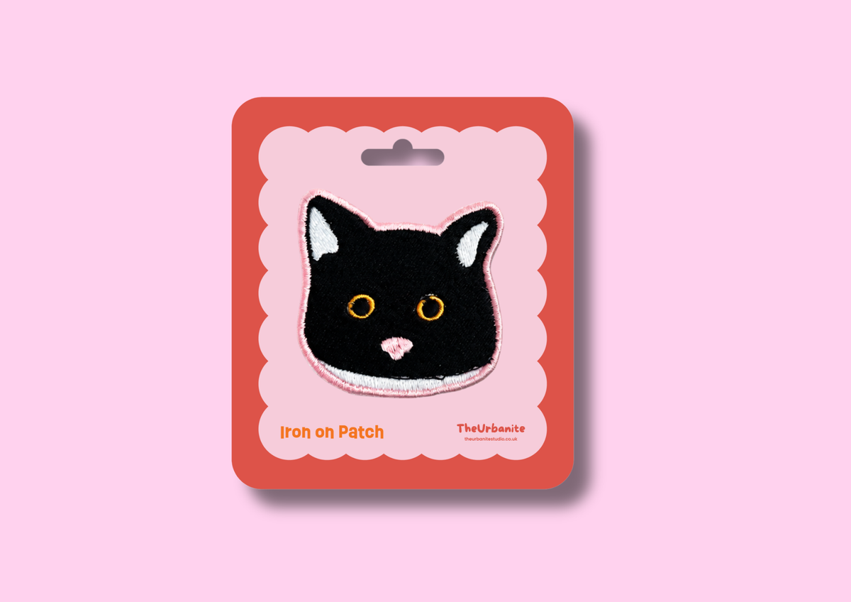 Black-and-white cat iron-on embroidered patch on TheUrbanite pink and coral packaging