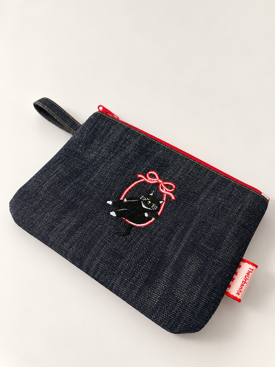 Cat 3.0 denim pouch from above showing embroidered cat motif and red zip