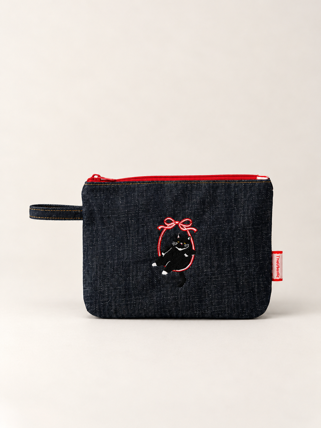 Cat 3.0 dark indigo denim pouch front view with embroidered black-and-white cat and red bow
