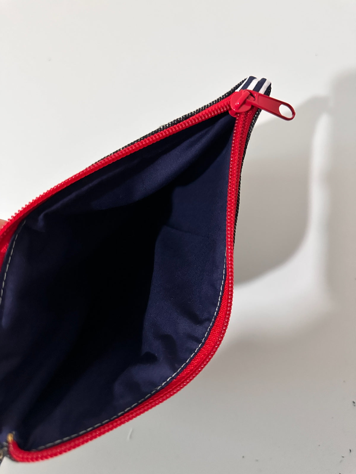 Inside view of large cat denim pouch with navy lining and red zipper