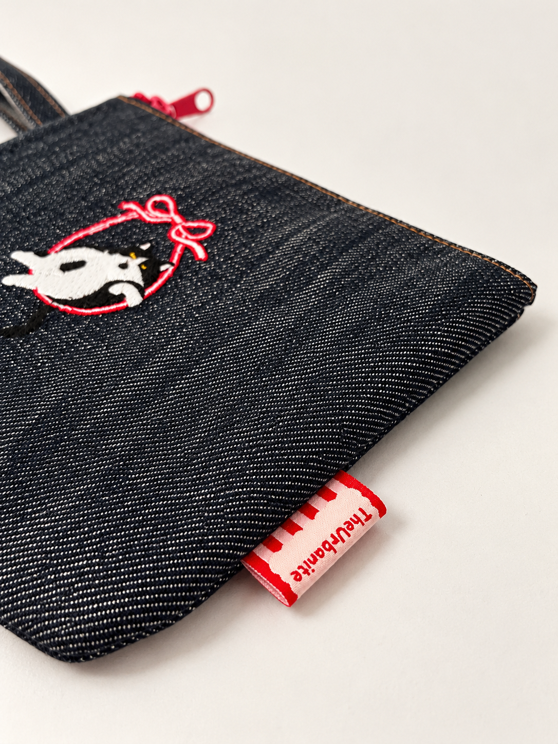Close-up of Cat Style 1 denim material, embroidered cat motif and TheUrbanite label