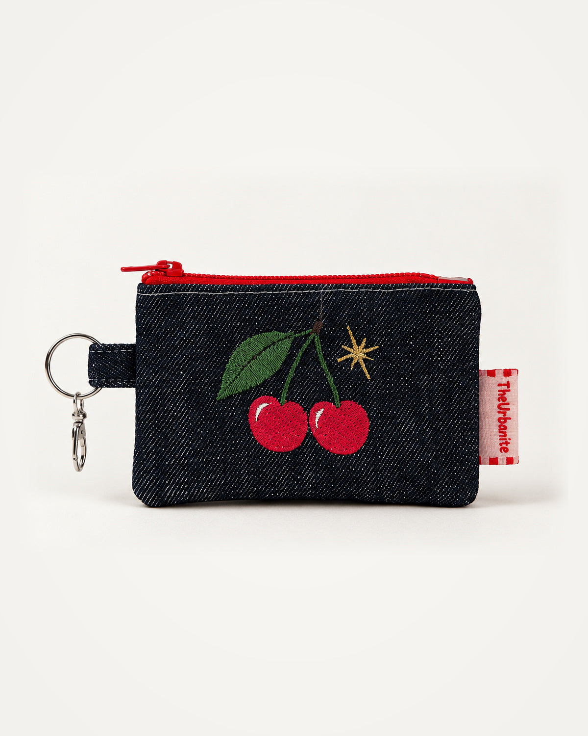 Full view of cherry embroidery coin purse including red zipper, keyring, clasp and branded label, framed centrally on neutral background