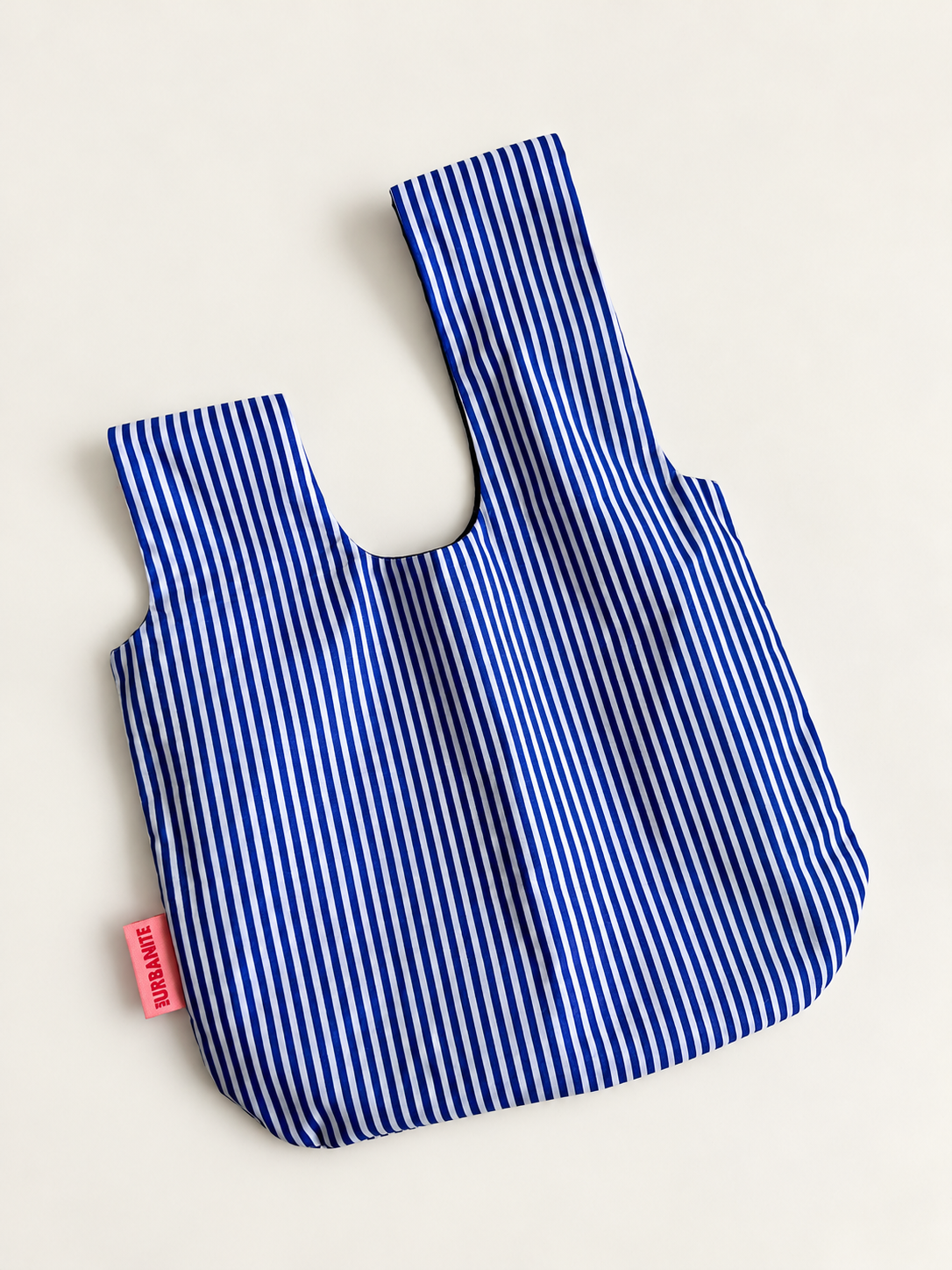 DALSTON blue and white striped knot bag opened flat showing asymmetric straps and pink TheUrbanite label