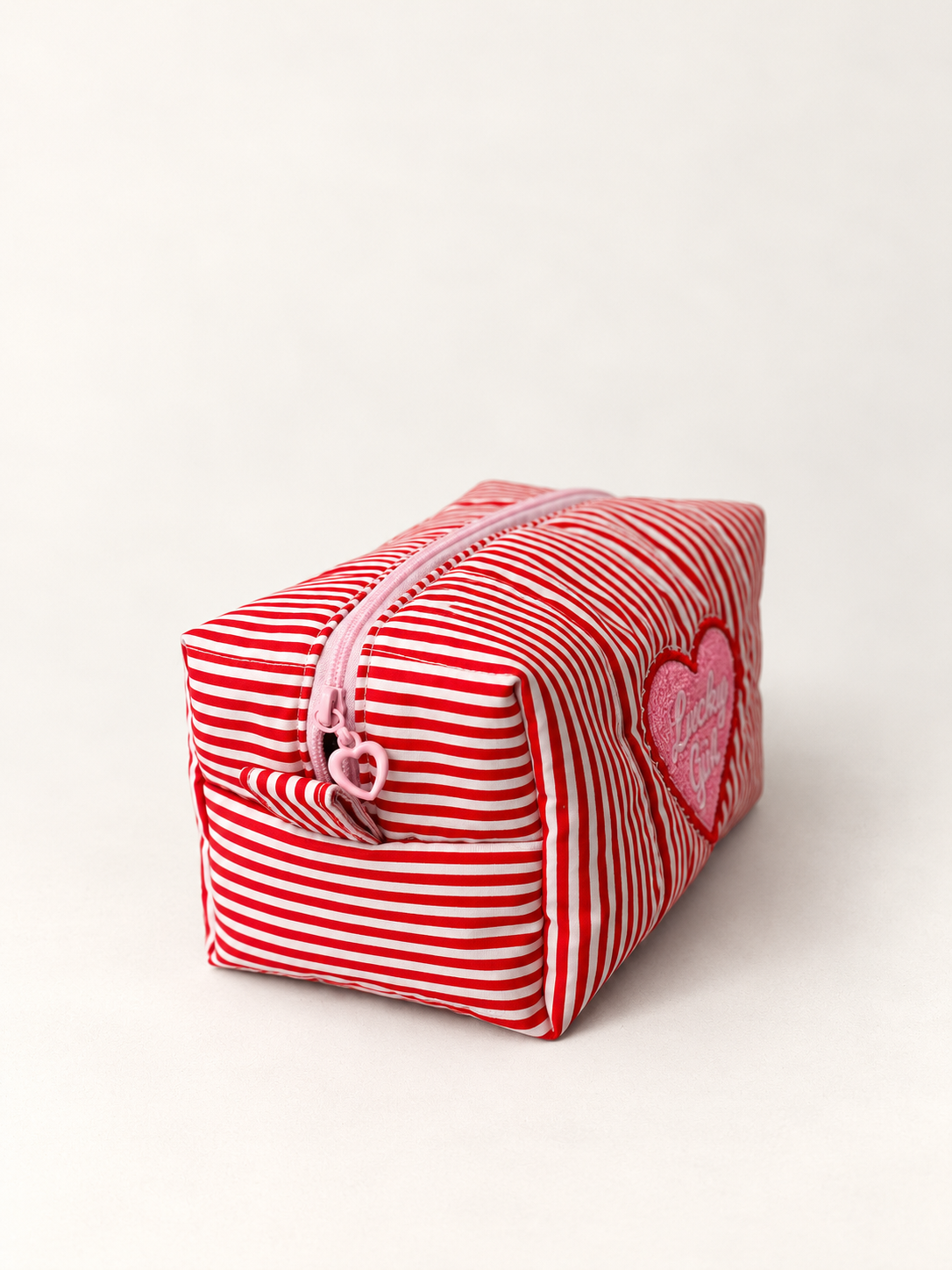 Three-quarter view of Lucky Girl striped makeup pouch showing pink heart zip pull